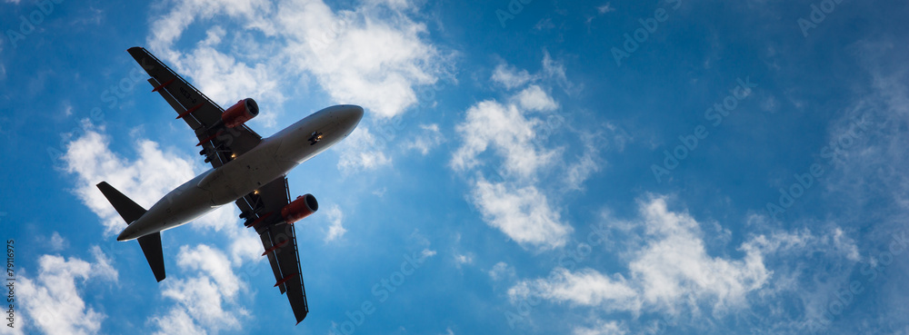 Fototapeta premium Dark silhouette of an airplane flying over the blue skies