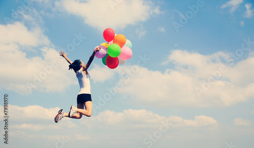 young asian woman mountain peak jumping with colored balloons 