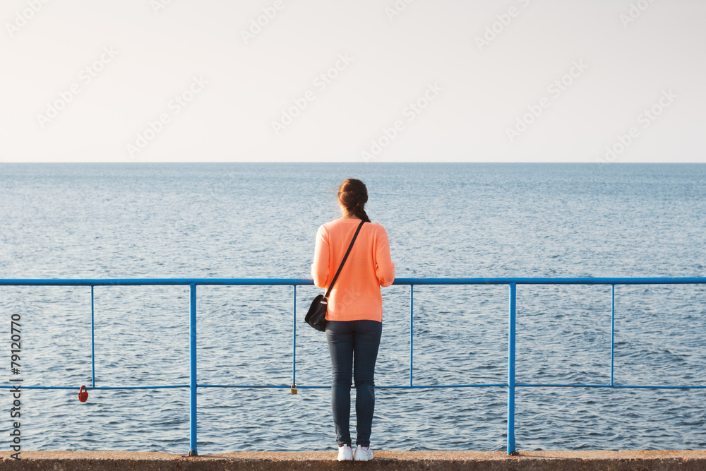 Girl on sea. Silhouette slim brunette, resting on pier. Summer vacation. Happy mood