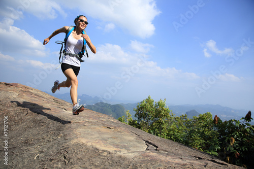 woman hiker running at on mountain peak rock