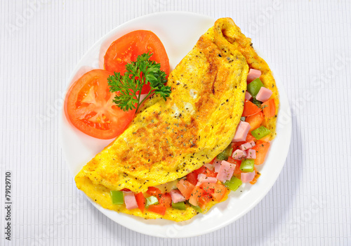 Delicious omelet with tomato, pepper, ham, basil