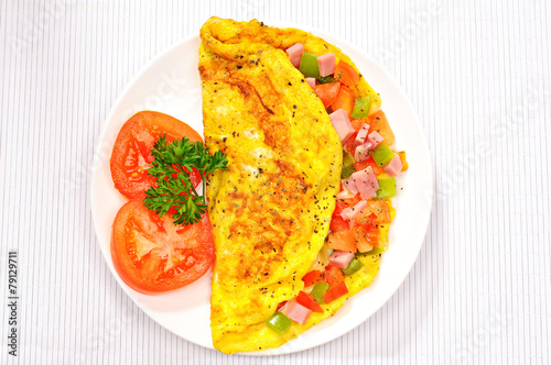 Delicious omelet with tomato, pepper, ham, basil