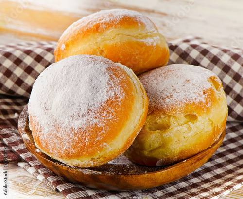 Sweet homemade Donuts with powdered sugar on a wooden plate.
