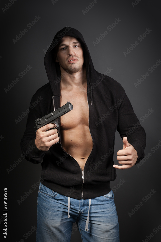 male gangster holding a gun isolated on gray background male gangster holding a gun isolated on gray background
