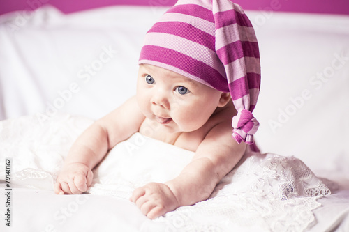 Canvas Print blue eyes baby showing tongue, beautiful girl in the cap