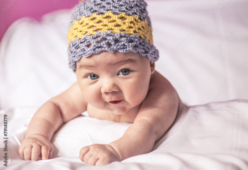 little girl lying on her stomach on the bed, and fun cap little girl lying on her stomach on the bed, and fun cap