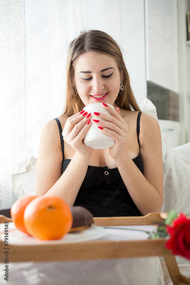 beautiful young woman having breakfast in bed and drinking coffe