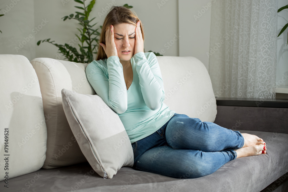tired woman lying on sofa and holding hands on head