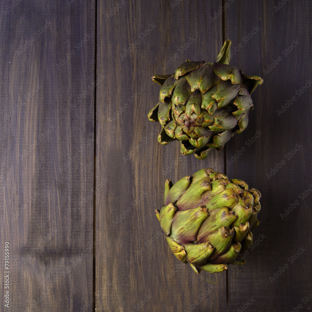 Fototapeta premium few artichokes on a wooden black table