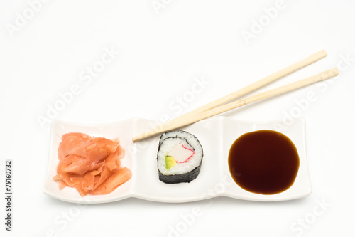 maki sushi with pickled ginger and soy sauce on white ceramic plate and chopsticks on white background