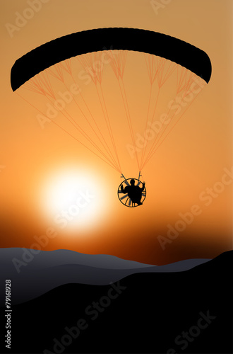 Flying paraglider silhouette at sunset