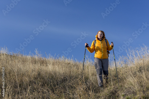 Female hiker walks downhill and enjoys warm sunlight