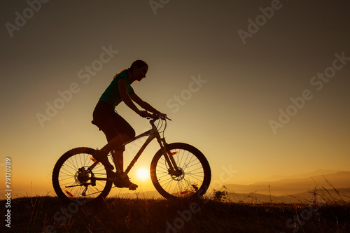 Biker-girl at the sunset on mountains