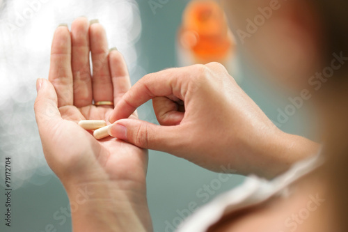 Young woman taking vitamins ginseng pill