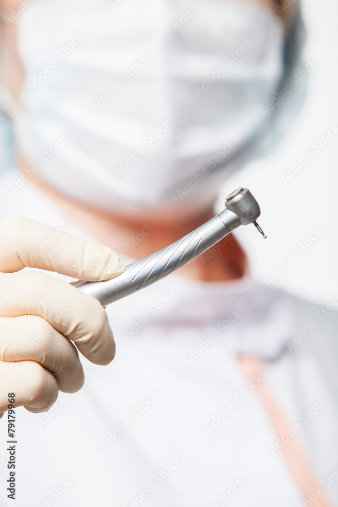 dentist woman with a mask holding tools ready to operate