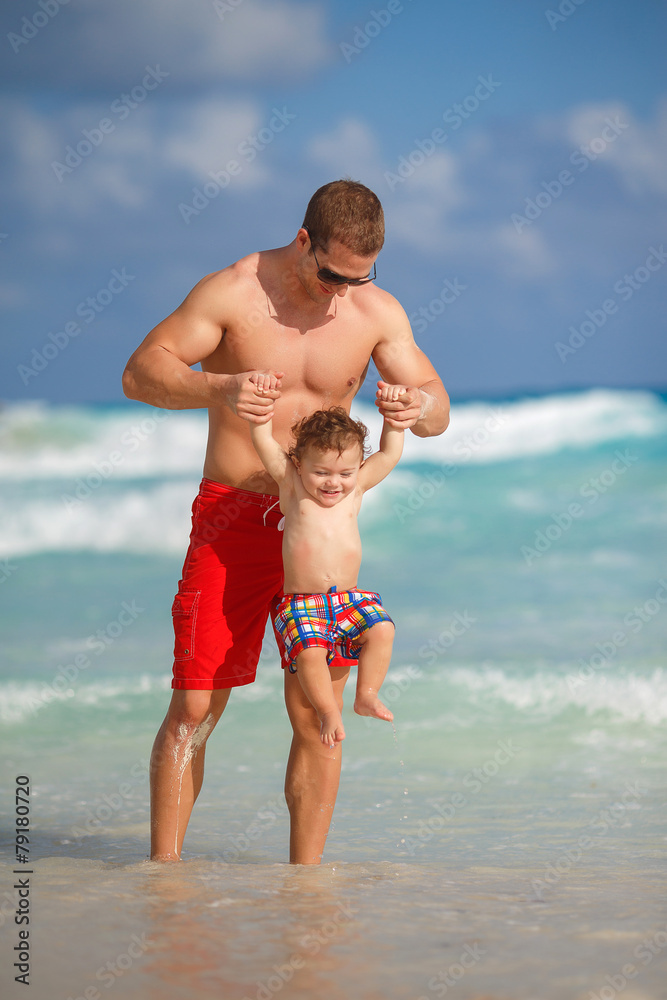 Young father with a young son play near the ocean. Young father with a young son play near the ocean.
