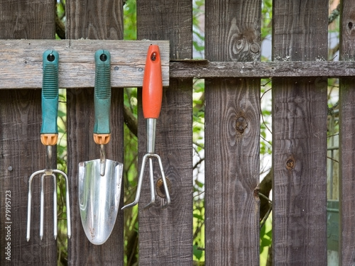 Gardening equipment hanging on a wooden rack.