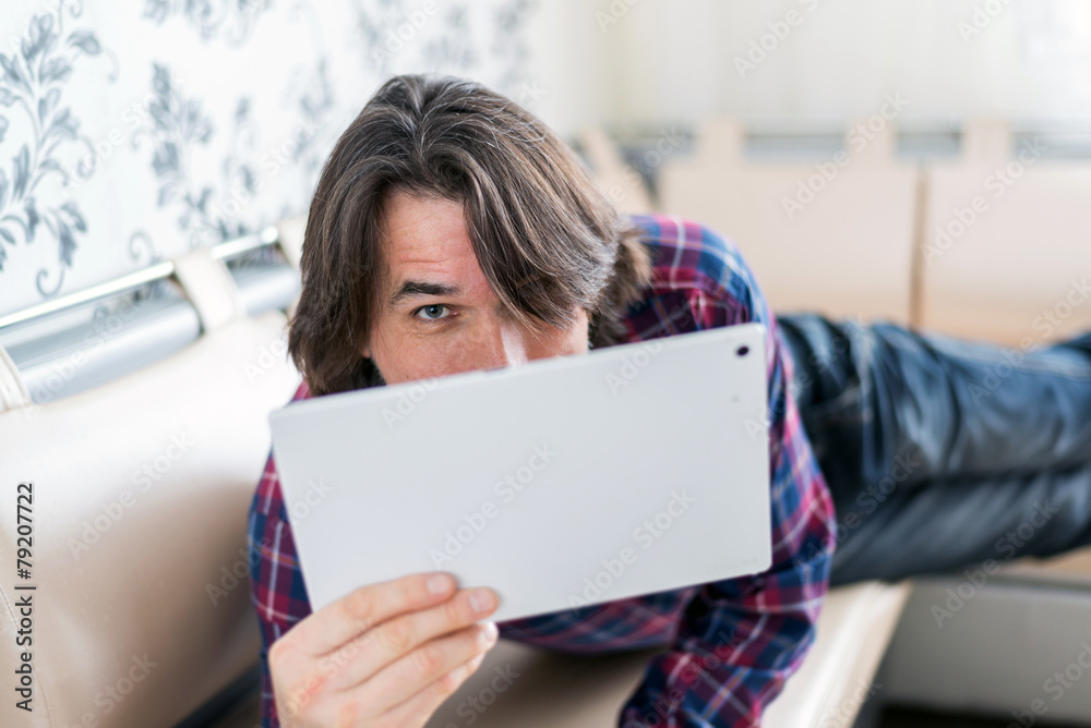 Man sitting in sofa using electronic tablet Man sitting in sofa using electronic tablet