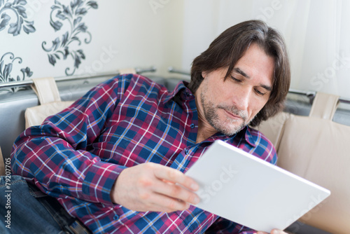 Man sitting in sofa using electronic tablet