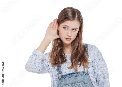 Young teenage fashion girl holds his hand near his ear and liste