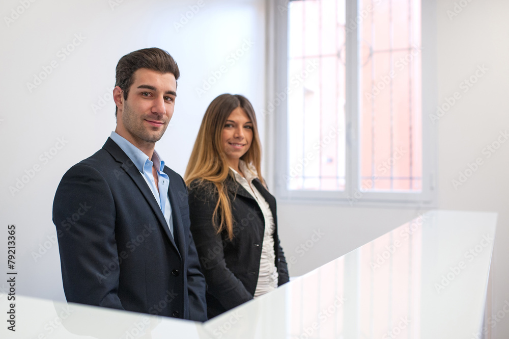 Young man and woman at reception desk in hospital waiting for pa Young man and woman at reception desk in hospital waiting for pa