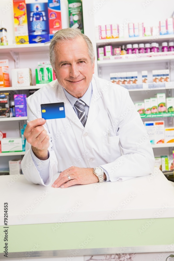 Smiling senior pharmacist holding credit card