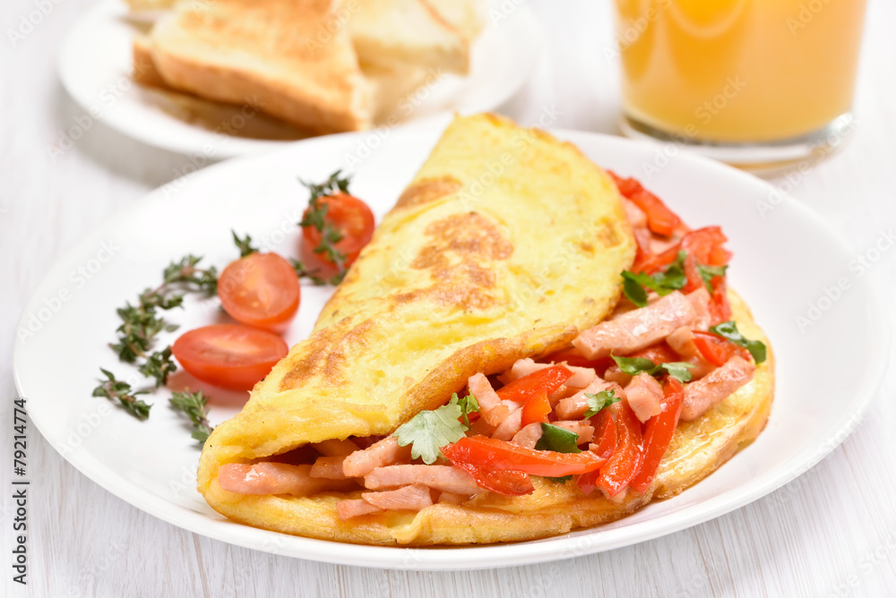 Egg omelette with vegetables and ham on white plate