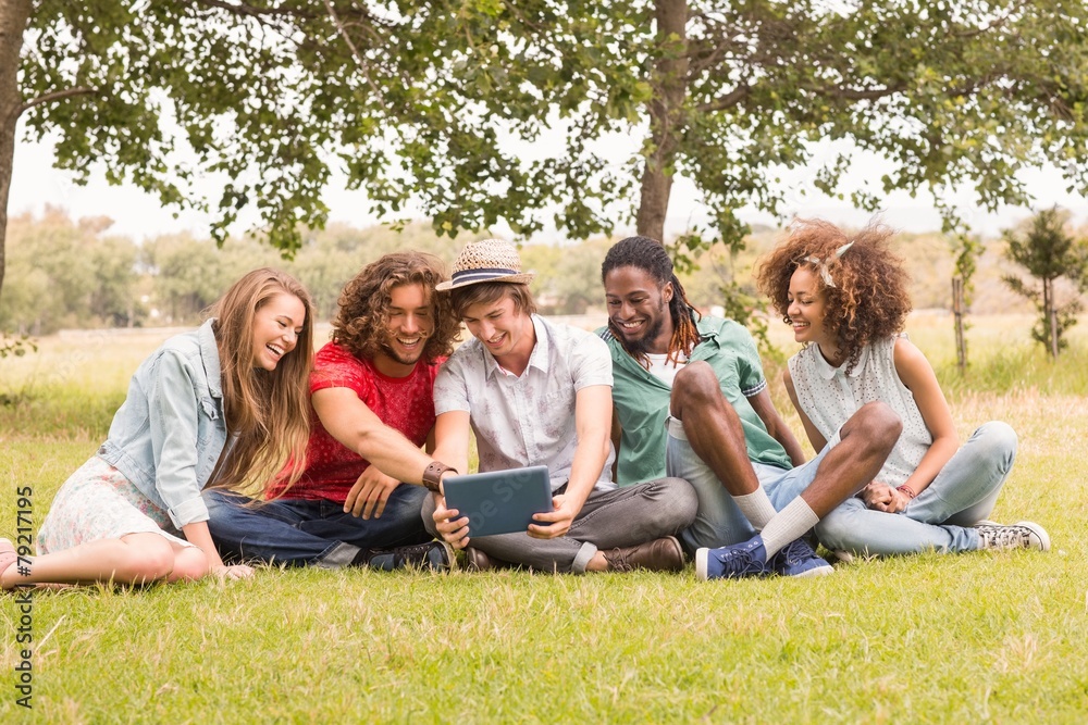 Happy friends in the park looking at tablet Happy friends in the park looking at tablet