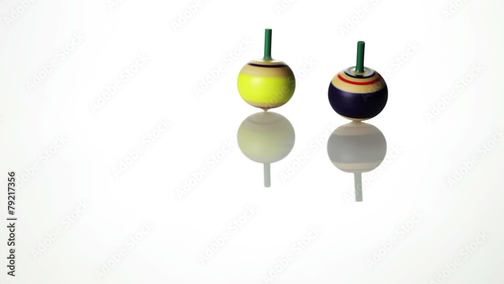 Spinning spin tops on white surface - back lit Spinning spin tops on white surface - back lit