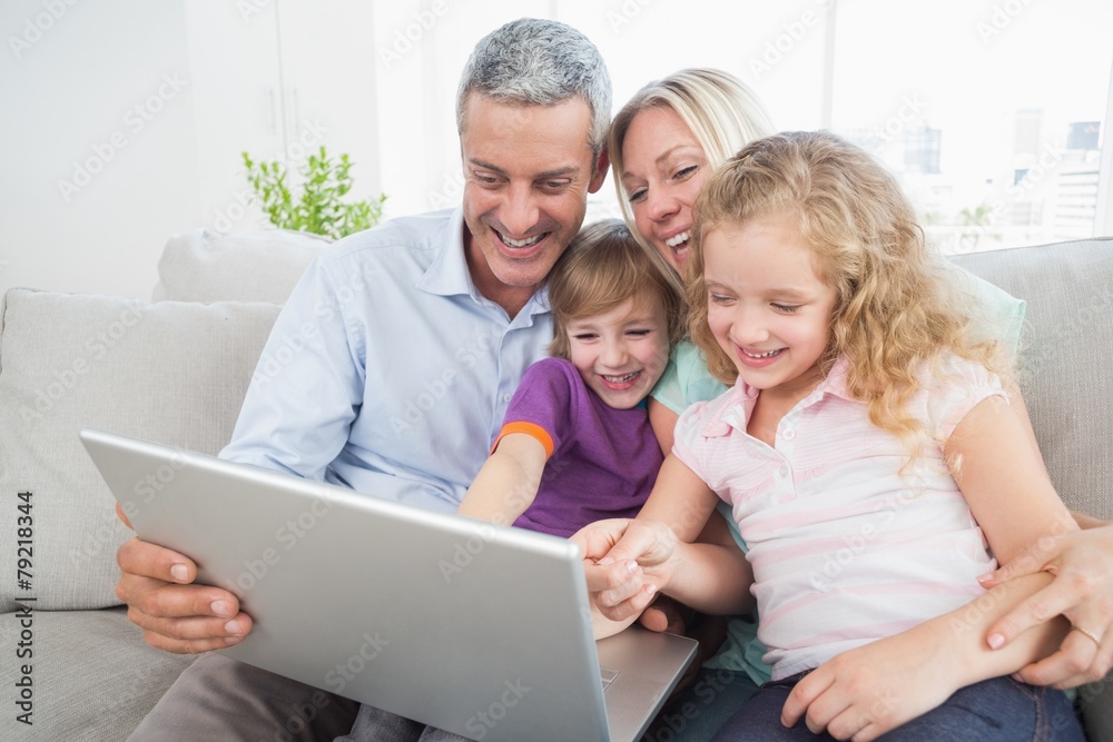 Family looking at laptop while sitting on sofa Family looking at laptop while sitting on sofa
