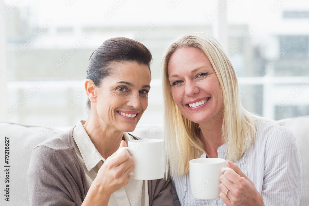 Smiling female friends having coffee in living room Smiling female friends having coffee in living room