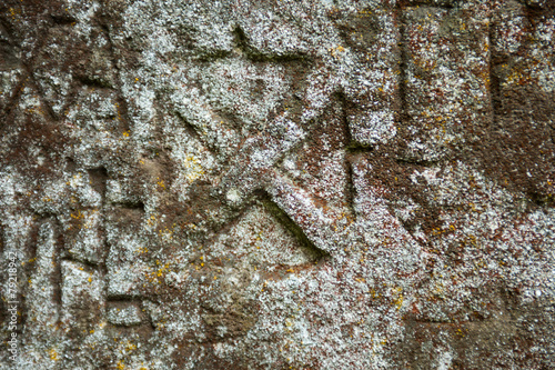 Moss-grown surface of the old stone cross photo