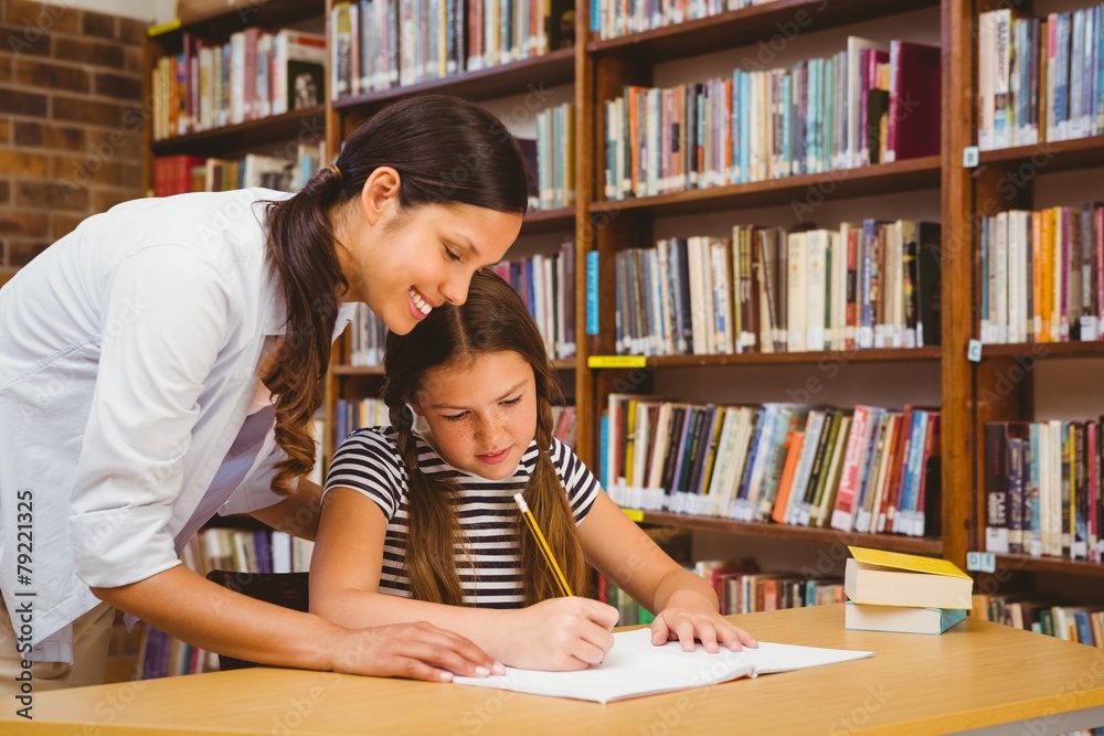 Teacher assisting girl with homework in library Teacher assisting girl with homework in library