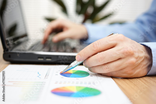 Close up of businessman hands reviewing business report and typi
