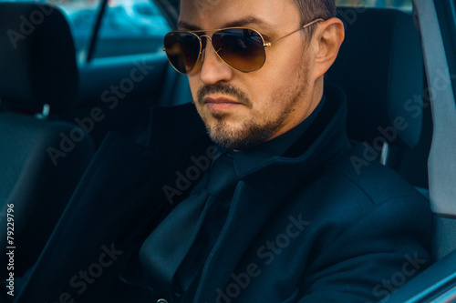 Elegant male in black suit driving car