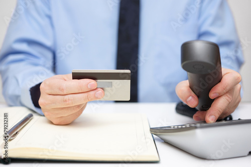 businessman with credit card dialing phone for support