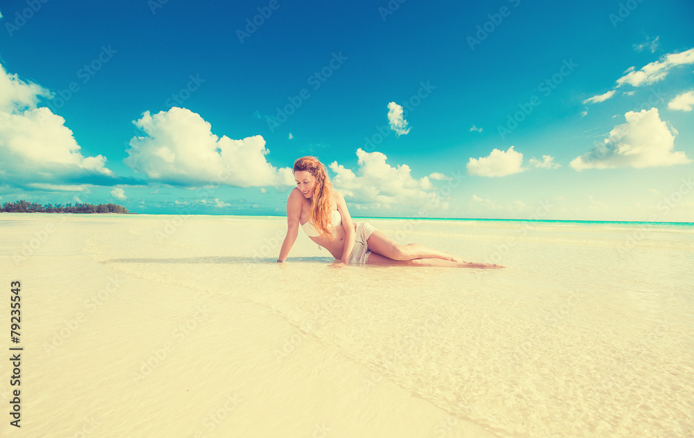 woman laying on beach yellow sand with tropical blue sky ocean b