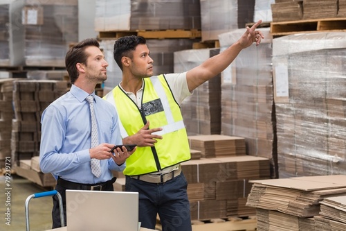 Warehouse worker showing something to his manager