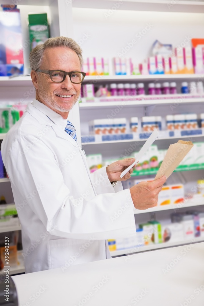 Smiling senior pharmacist holding prescription
