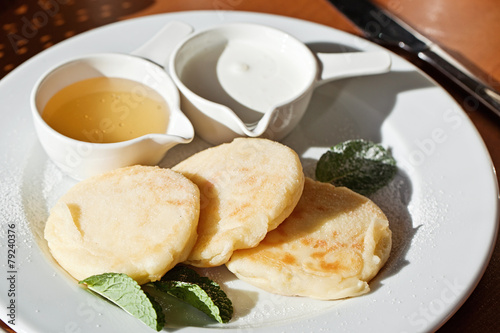Cheese pancakes with sour cream and honey