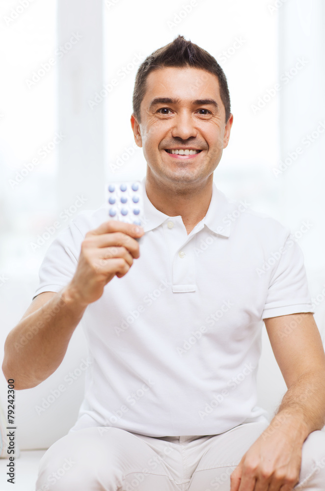 happy man showing pack of pills at home happy man showing pack of pills at home