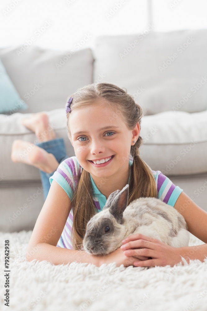 Smiling girl with rabbit lying on rug in living room Smiling girl with rabbit lying on rug in living room
