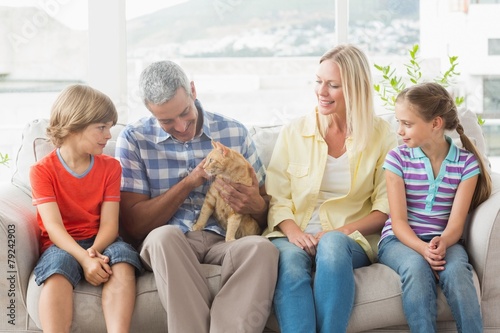 Family sitting with cat on sofa at home