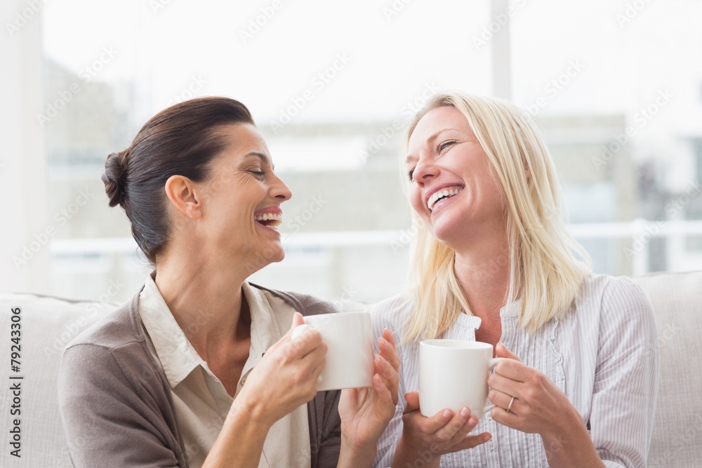 Women gossiping while having coffee in living room Women gossiping while having coffee in living room
