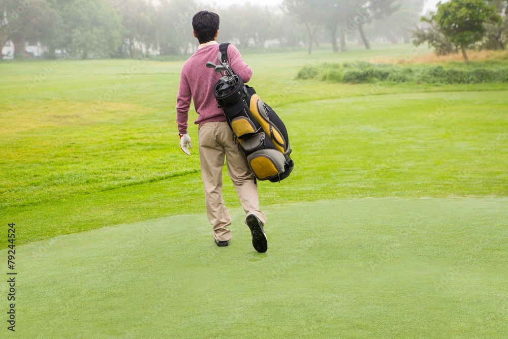 Golfer walking away holding golf bag Golfer walking away holding golf bag