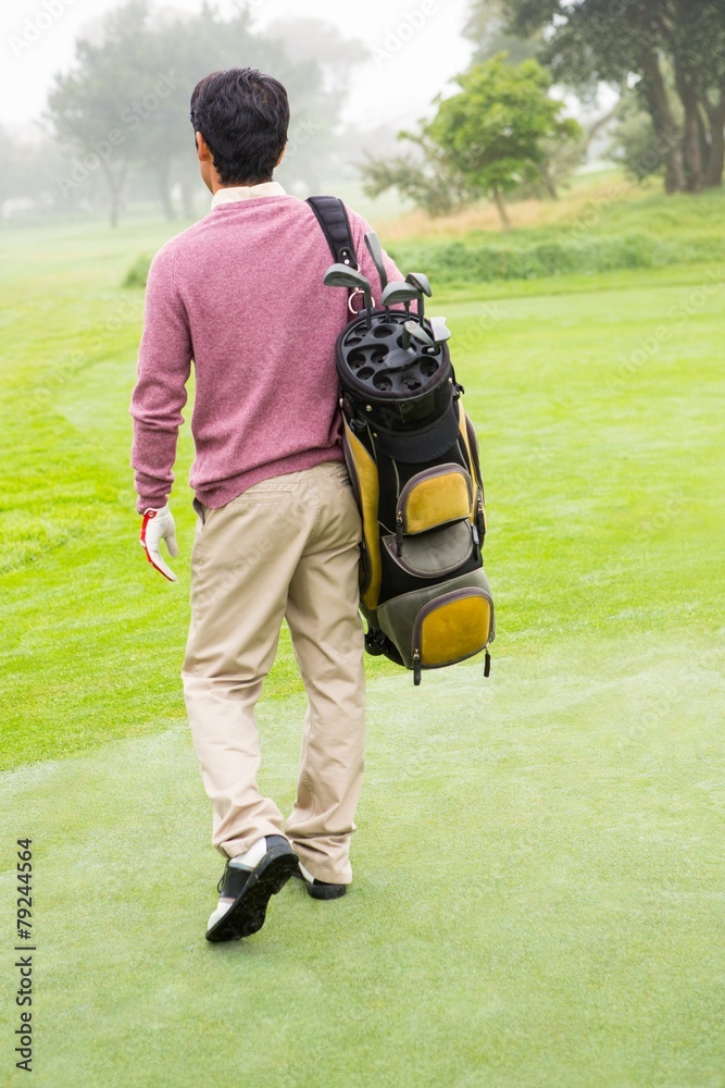 Fototapeta premium Golfer walking away holding golf bag