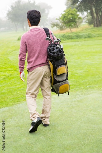 Golfer walking away holding golf bag