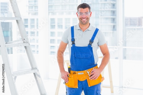 Smiling repairman in overalls at bright office