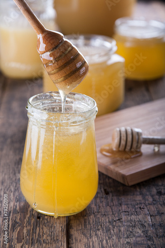 Honey in a jar with a wooden honey dipper.