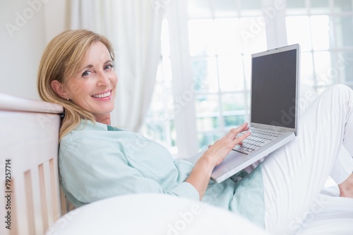 Happy woman using laptop in her bed